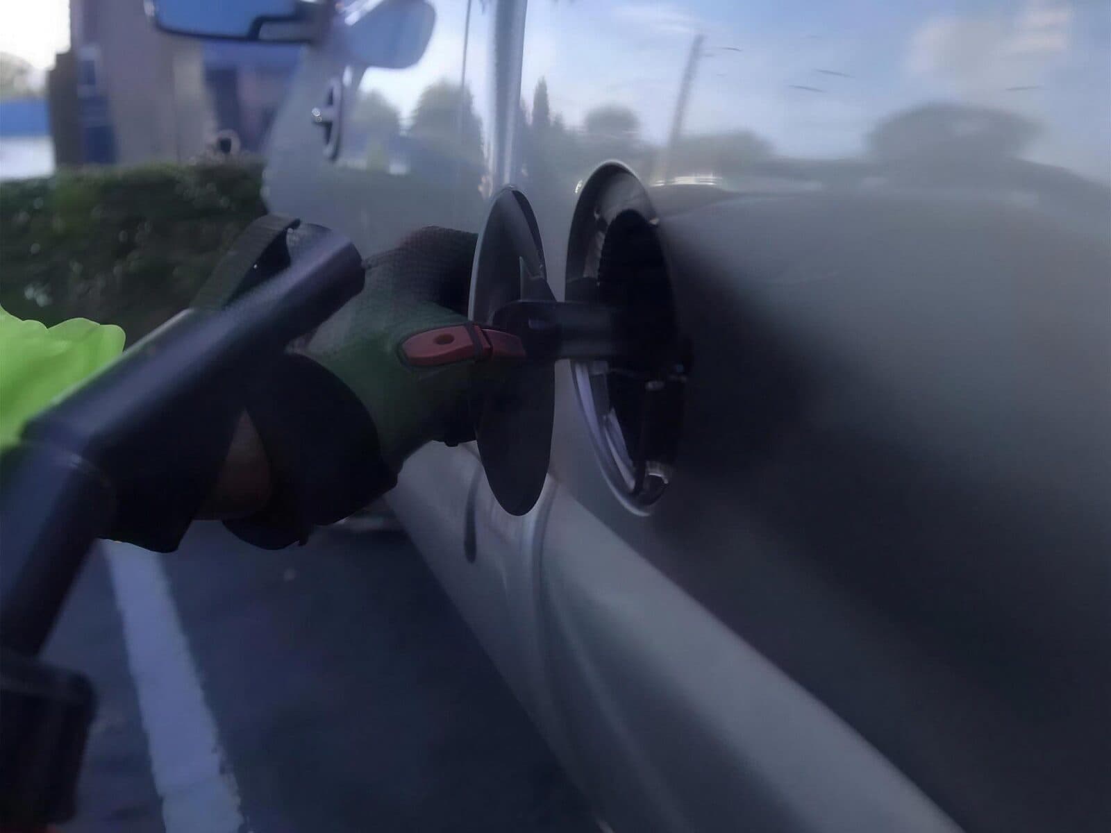 Pouring fuel from a jerry can into a car's filler neck at the roadside