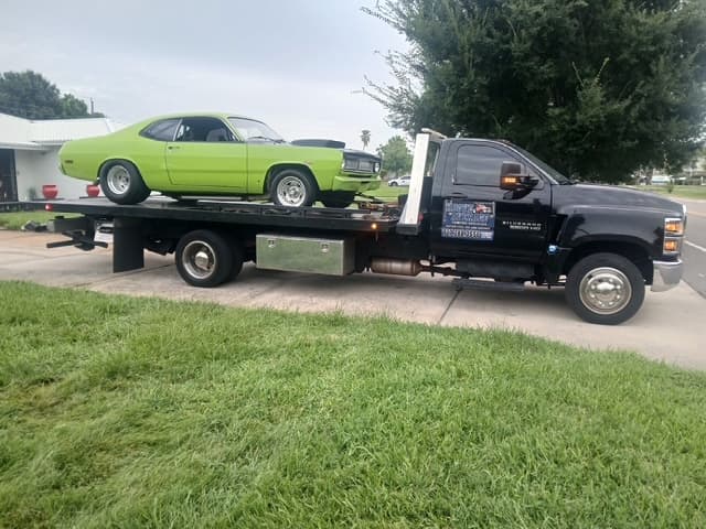 Lime green Plymouth Duster muscle car strapped down on the flatbed