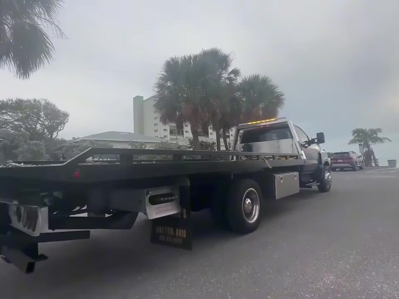 The empty flatbed tilted and ready to load, palms and open sky behind it