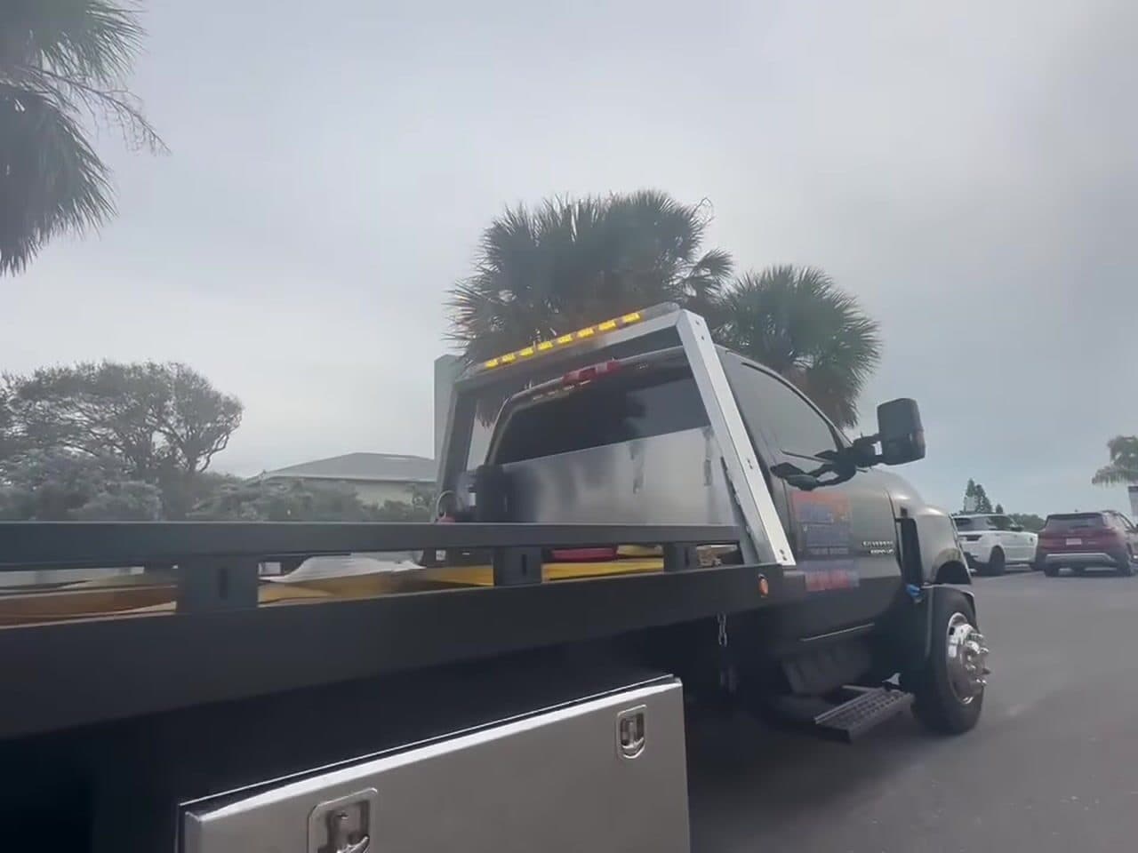 The flatbed seen from behind, deck empty and level, parked under palms